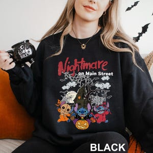 A woman wearing a black sweatshirt with a Halloween-themed design, including characters from the movie "Nightmare on Main Street".