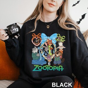 A woman wearing a black sweatshirt with a colorful graphic of cartoon animals and the word "Zootopia" printed on it.