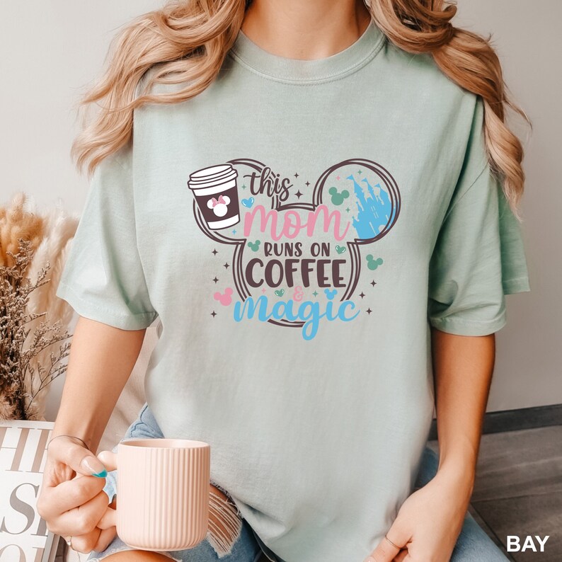 a woman holding a cup of coffee while wearing a mickey mouse shirt