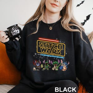 A woman wearing a black sweatshirt with a Star Wars-themed design, including characters from the Star Wars franchise.