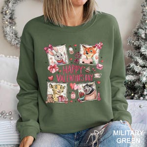 A woman wearing a green sweatshirt with a graphic design featuring cartoon animal characters and the text "Happy Valentine's Day".