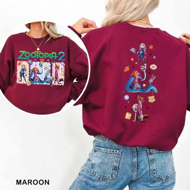 A person wearing a maroon sweater with a colorful graphic design featuring cartoon characters and various other elements.