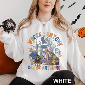 A woman wearing a white sweatshirt with a colorful graphic design featuring cartoon characters and text.