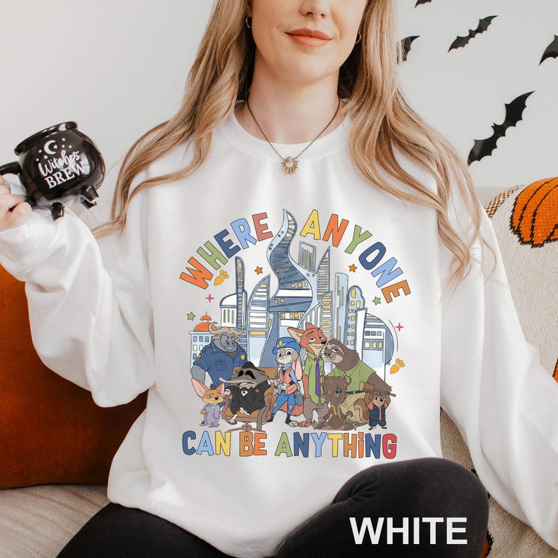 A woman wearing a white sweatshirt with a colorful graphic design featuring cartoon characters and text.