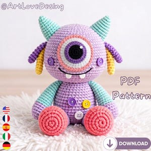 May include: A handmade crochet monster doll in shades of purple, teal, yellow, and pink. The one-eyed monster has button details and is sitting on a white fluffy surface. The text "PDF Pattern" and "Download" are visible.