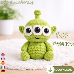 Puede incluir: Un juguete alienígena verde tejido a ganchillo con tres grandes ojos negros, orejas pequeñas y una pequeña antena. El texto "PDF Pattern" se muestra en el lado derecho de la imagen, con un icono de descarga debajo. El juguete está sobre una superficie blanca y esponjosa.