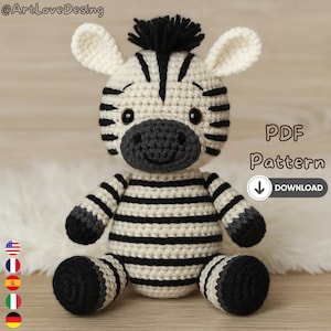 Può includere: Un peluche di zebra all'uncinetto con strisce nere e bianche, zoccoli neri e una criniera nera. La zebra ha un muso grigio ed è seduta. L'immagine include il testo "PDF Pattern" e "Download".