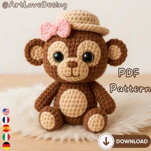 Op de afbeelding: Een gehaakte apenpop met een beige hoed en een roze strik. De aap is bruin en beige met grote zwarte ogen en een beige snuit. De tekst "PDF Pattern" en een downloadknop zijn zichtbaar.