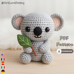 Può includere: Un koala all'uncinetto grigio con l'interno delle orecchie rosa, che tiene una foglia verde. Il koala ha occhi neri e un naso nero. L'immagine include il testo "PDF Pattern" e un'icona di download.