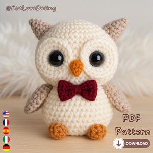 Può includere: Un gufo all'uncinetto color crema con grandi occhi neri, un papillon bordeaux, becco e zampe arancioni. Il gufo ha accenti beige sulle ali e sulle orecchie. L'immagine include il testo "PDF Pattern" e un'icona di download.