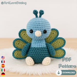 Puede incluir: Un juguete de pavo real tejido a mano en tonos azules, verdes y crema. El pavo real tiene grandes ojos negros, un pico color crema y una cola en forma de abanico. La imagen incluye el texto "PDF Pattern" y una flecha de descarga.