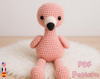May include: A handmade pink crochet flamingo with a black and white beak and black eyes. The flamingo is sitting on a white fluffy surface. The image includes the text "PDF Pattern" and a download arrow.