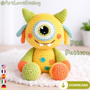 Puede incluir: Un monstruo de ganchillo amarillo hecho a mano con un ojo grande, detalles verdes y azules, y detalles naranjas y verdes. El monstruo tiene una boca sonriente y está adornado con botones coloridos. El texto "PDF Pattern" y "Download" son visibles.