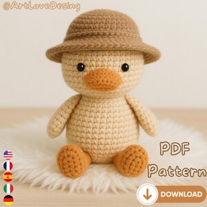 May include: A crocheted duck toy wearing a brown hat, with an orange beak and feet. The duck is sitting on a white fluffy surface. The image includes the text "PDF Pattern" and a download button.