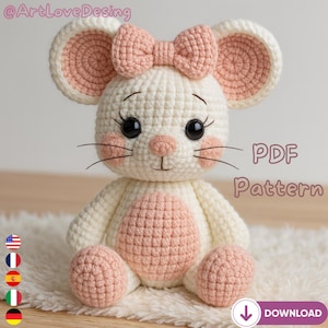 Puede incluir: Un ratón de ganchillo en crema y rosa. El ratón tiene grandes ojos negros, mejillas rosas y un lazo a juego. El texto "PDF Pattern" es visible. El juguete está sobre una superficie blanca y esponjosa. Un artículo hecho a mano.