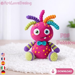 May include: A handmade, crocheted monster doll in bright pink with yellow spots. It has green and blue eyes, a blue bow tie, and colorful antennae. The text "PDF Pattern" is visible.