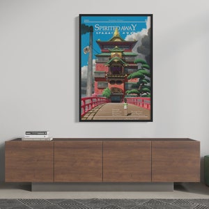 May include: A framed poster with a minimalist design featuring a red and gold building with a bridge leading to it. The poster is titled "Spirited Away" and includes the film's credits.
