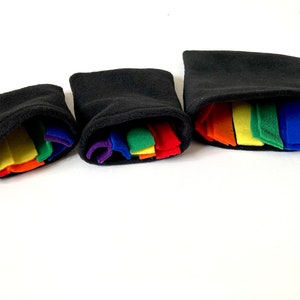 May include: Three black fleece pouches with rainbow colored fabric strips inside. The pouches are different sizes.