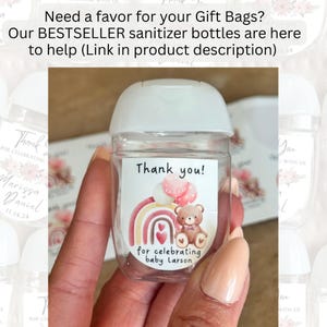 May include: A clear sanitizer bottle with a white cap and a label that reads "Thank you!" with a rainbow, balloons, and a teddy bear illustration. The label also says "for celebrating baby Larson."