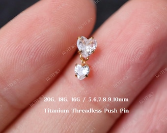 May include: A pair of gold heart-shaped earrings with clear cubic zirconia stones. The earrings are on a titanium threadless push pin. The earrings are available in 20 gauge, 18 gauge, and 16 gauge. The earrings are also available in sizes 5mm to 10mm.