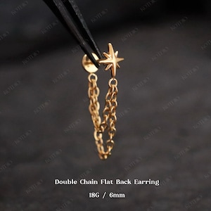 May include: A gold-colored double chain flat back earring. The earring features a star-shaped top and two dangling chains. The text "Double Chain Flat Back Earring" and "18G / 6mm" are visible.