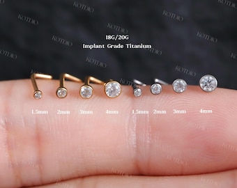 May include: An assortment of nose studs in gold and silver, each with a clear, round gemstone. Sizes vary from 1.5mm to 4mm. The image includes the text "18G/20G Implant Grade Titanium".