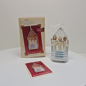 May include: A Hallmark Keepsake ornament featuring four angels singing in a white and silver church. The ornament has a moving and musical feature. The box and card read "Angels We Have Heard".