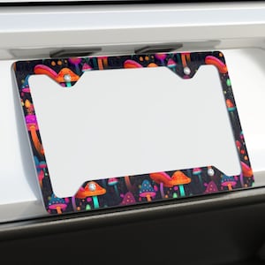 May include: A white car with a black license plate frame featuring a colorful mushroom pattern. The frame has a white background and a black border.