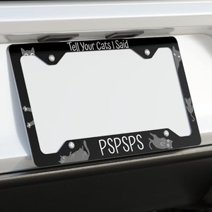 Puede incluir: Marco de matrícula negro con el texto "Tell Your Cats I Said PSPSPS" y una silueta de un gato a cada lado.
