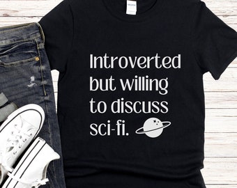 May include: Black t-shirt with white text that reads "Introverted but willing to discuss sci-fi." A small white planet with rings is next to the text.