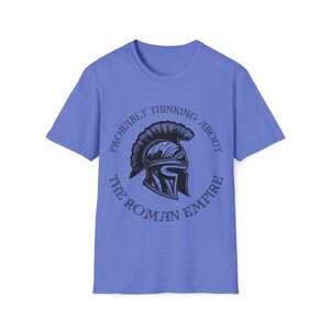 May include: A light blue t-shirt with a graphic of a Roman helmet inside a circle with the text "Probably thinking about the Roman Empire".