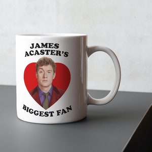 May include: White ceramic mug with a red heart featuring a photo of James Acaster. The text "JAMES ACASTER'S BIGGEST FAN" is printed on the mug.