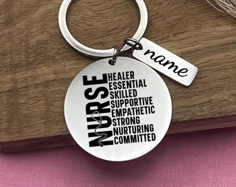 May include: Silver keychain with a round charm that says "NURSE" with a stethoscope symbol and the words "HEALER ESSENTIAL SKILLED SUPPORTIVE EMPATHETIC STRONG NURTURING COMMITTED" around it. A smaller tag attached to the keychain says "name".