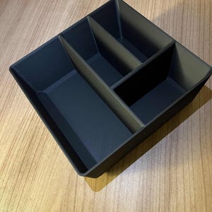 Op de afbeelding: Een zwarte plastic dienblad met drie compartimenten. Het dienblad is verdeeld in drie secties, elk met een andere grootte.