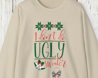 May include: A cream-coloured sweatshirt featuring the text "I don't do UGLY Sweater" in green and red. The design includes green snowflake shapes, bells, and mittens. The sweatshirt is displayed on a wooden background with pine needles.