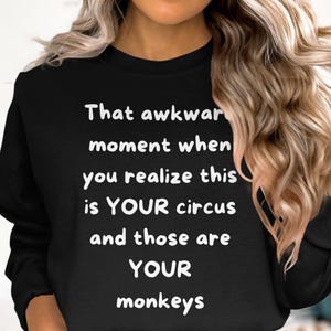 Op de afbeelding: Zwart sweatshirt met de witte tekst: "That awkward moment when you realize this is YOUR circus and those are YOUR monkeys". De sweatshirt heeft een ronde hals.