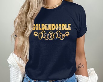 Könnte beinhalten: Marineblaues T-Shirt mit dem Text "GOLDENDOODLE MOM" in Gelb und Blau, mit Pfotenabdrücken. Das T-Shirt hat hochgekrempelte Ärmel.