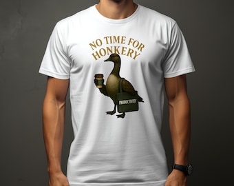 Op de afbeelding: Wit T-shirt met een bruine eend die een kopje koffie vasthoudt en een groene tas met de tekst "Productiviteit". De tekst op het shirt is "No Time For Honkery".