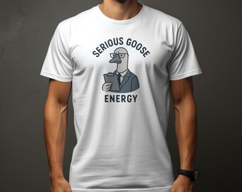 Op de afbeelding: Wit T-shirt met een cartoon-gans die een bril en een pak draagt en een klembord vasthoudt. De tekst "SERIOUS GOOSE ENERGY" is op het shirt gedrukt.