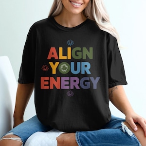 May include: A black t-shirt with the text "ALIGN YOUR ENERGY" in rainbow colors. The text is surrounded by small lotus flower symbols.