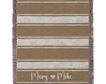 May include: A woven throw blanket with a brown and white striped pattern. The blanket has a fringe border and the text "Mary ♥ Mike" is printed on the bottom.