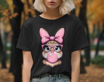 Może przedstawiać: Czarny t-shirt z kreskówkową ilustracją kota w różowych okularach, różowej kokardce i dmuchającego różową bańkę.