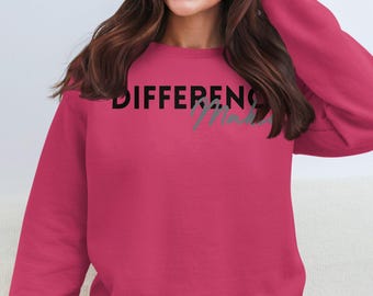May include: A magenta sweatshirt with the words "DIFFERENCE Made" printed across the chest in black and gray. The sweatshirt has long sleeves and a crew neck. The overall theme is casual wear.