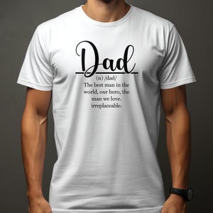 Puede incluir: Camiseta blanca con texto negro que dice "Dad (n) /dad/ The best man in the world, our hero, the man we love. irreplaceable."