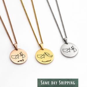 May include: Three round pendant necklaces with chain. The pendants are rose gold, gold, and silver. Each pendant features a map outline with a connecting line and heart symbol. One pendant has the initials "S".