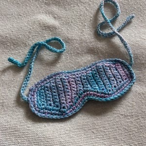 May include: A blue and purple crocheted sleep mask with a tie-on strap.