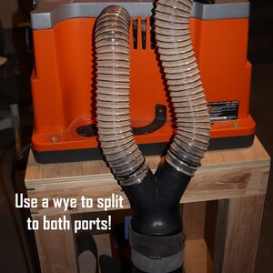 Pu&ograve; includere: Primo piano di una levigatrice per legno con due porte di aspirazione della polvere. La macchina &egrave; collegata a un tubo di aspirazione della polvere nero con uno splitter a forma di Y. Il testo "Use a wye to split to both ports!" &egrave; visibile nell'immagine.