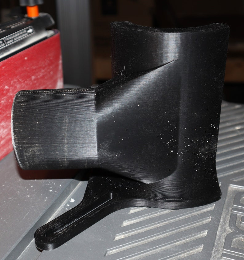 Pu&ograve; includere: Un oggetto nero stampato in 3D con una forma curva e un manico. L'oggetto &egrave; fatto di plastica e ha una superficie liscia.
