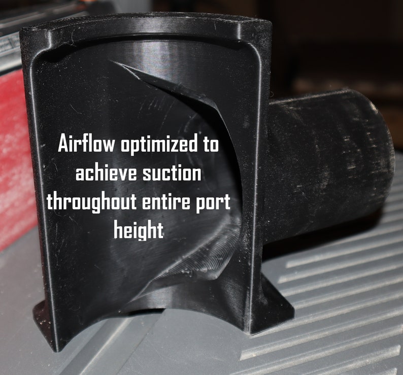 Pu&ograve; includere: Un collettore di polvere in plastica nera con un design curvo. Il testo "Airflow optimized to achieve suction throughout entire port height" &egrave; stampato sul collettore.