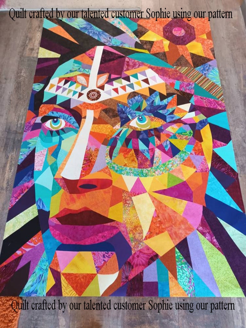以下が含まれることがあります： 額に白い線が引かれた顔の幾何学模様が施されたカラフルなキルト。キルトは赤、オレンジ、黄色、緑、青、紫、黒の様々な生地で作られています。このキルトは、才能のあるお客様がパターンを使って製作しました。